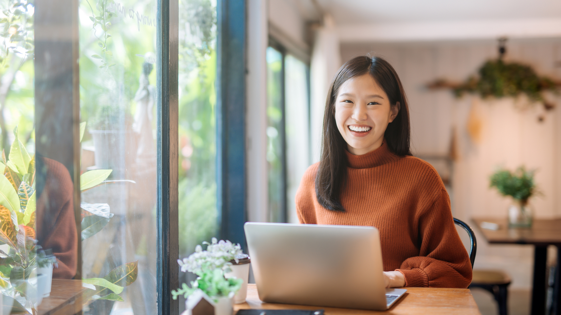 Asian woman smiling while working on laptop